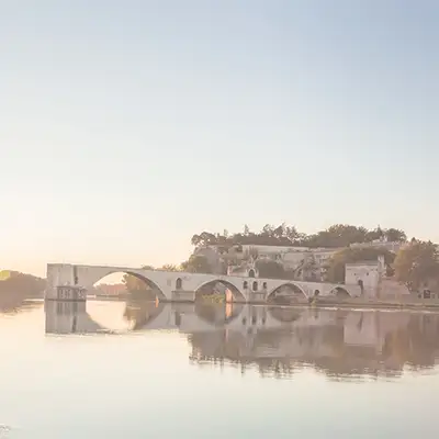 Landschaftsbild Frankreich mit einem Gewässer und einer Brücke, die bis in die Mitte des Gewässers geht.